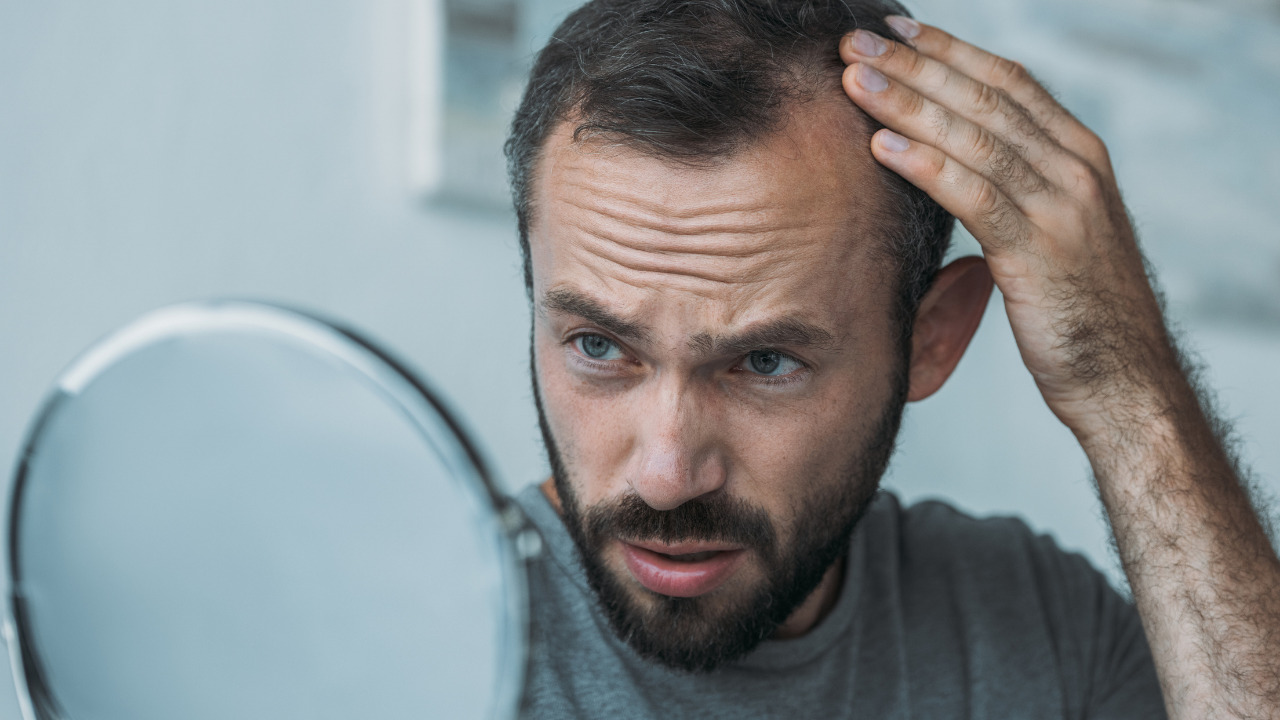 鏡で髪の毛を見ている男性