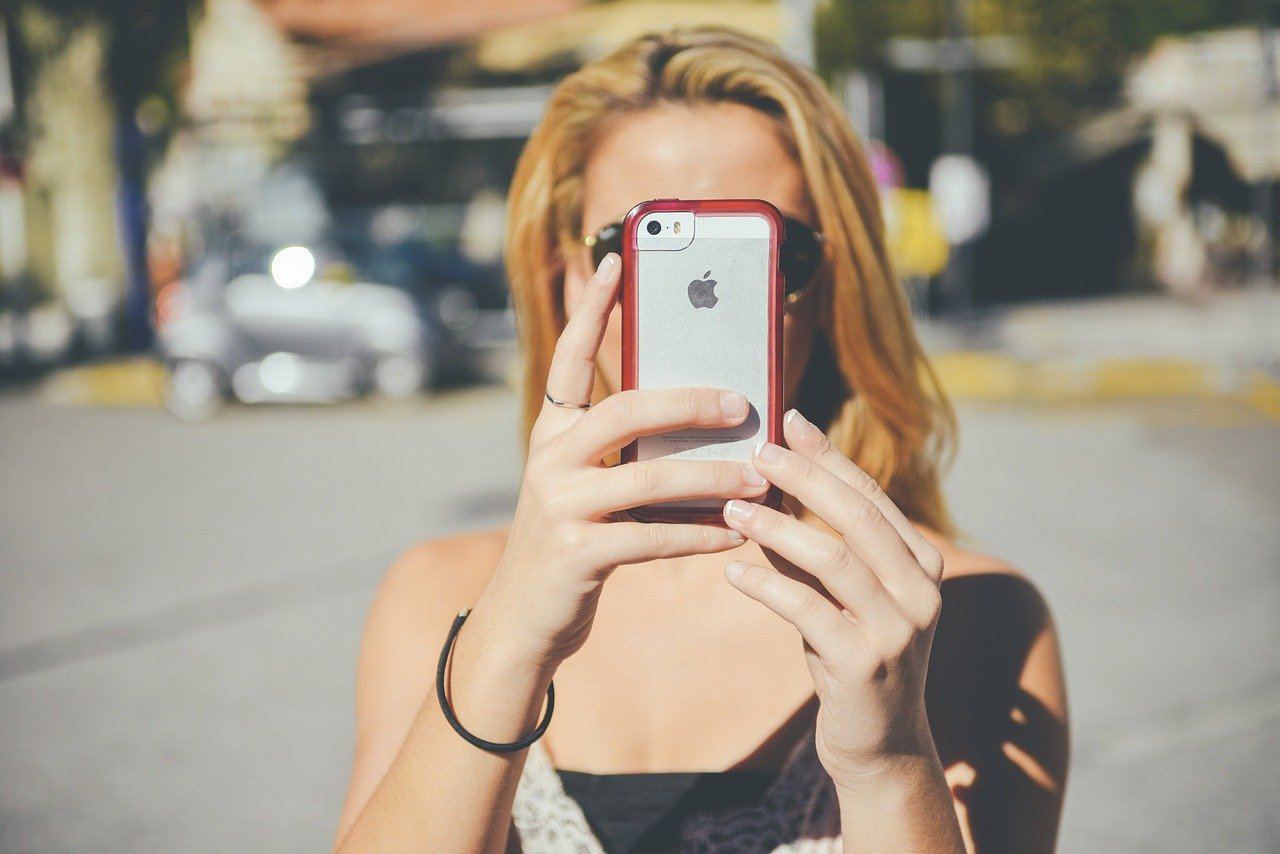 スマホでこちらを撮影する女性